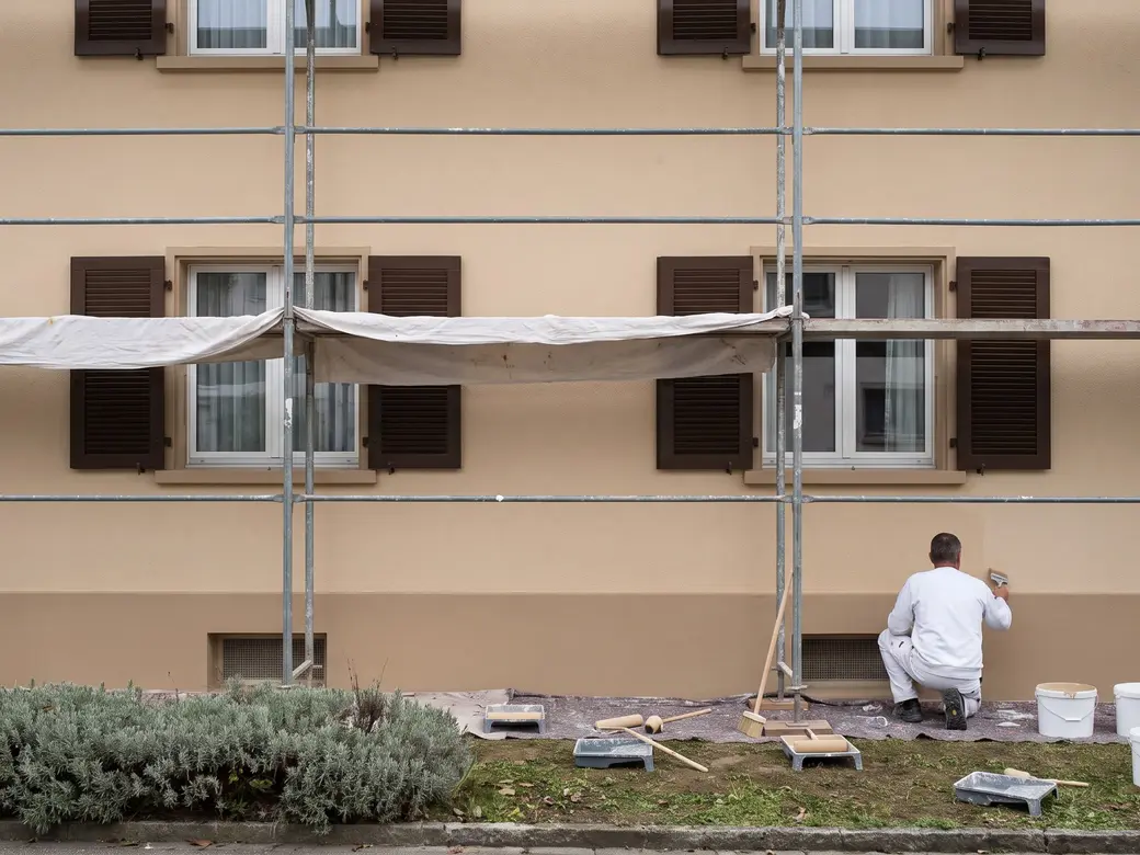 Fassade eines Einfamilienhauses mit Gerüst, frisch gestrichen, Fensterläden in einem dunkleren Ton